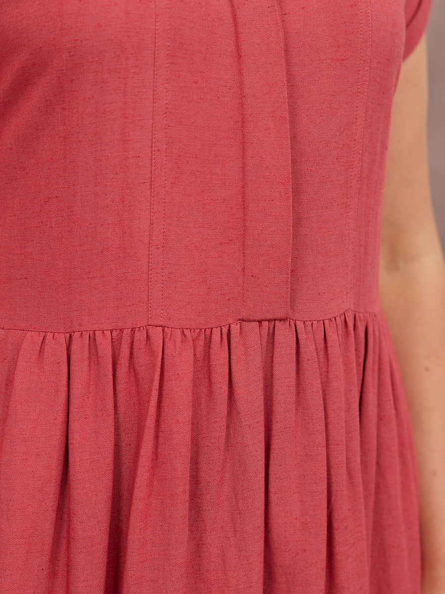 Close-up of a dusty rose linen dress bodice with vertical seam detail and gathered skirt at drop waist.