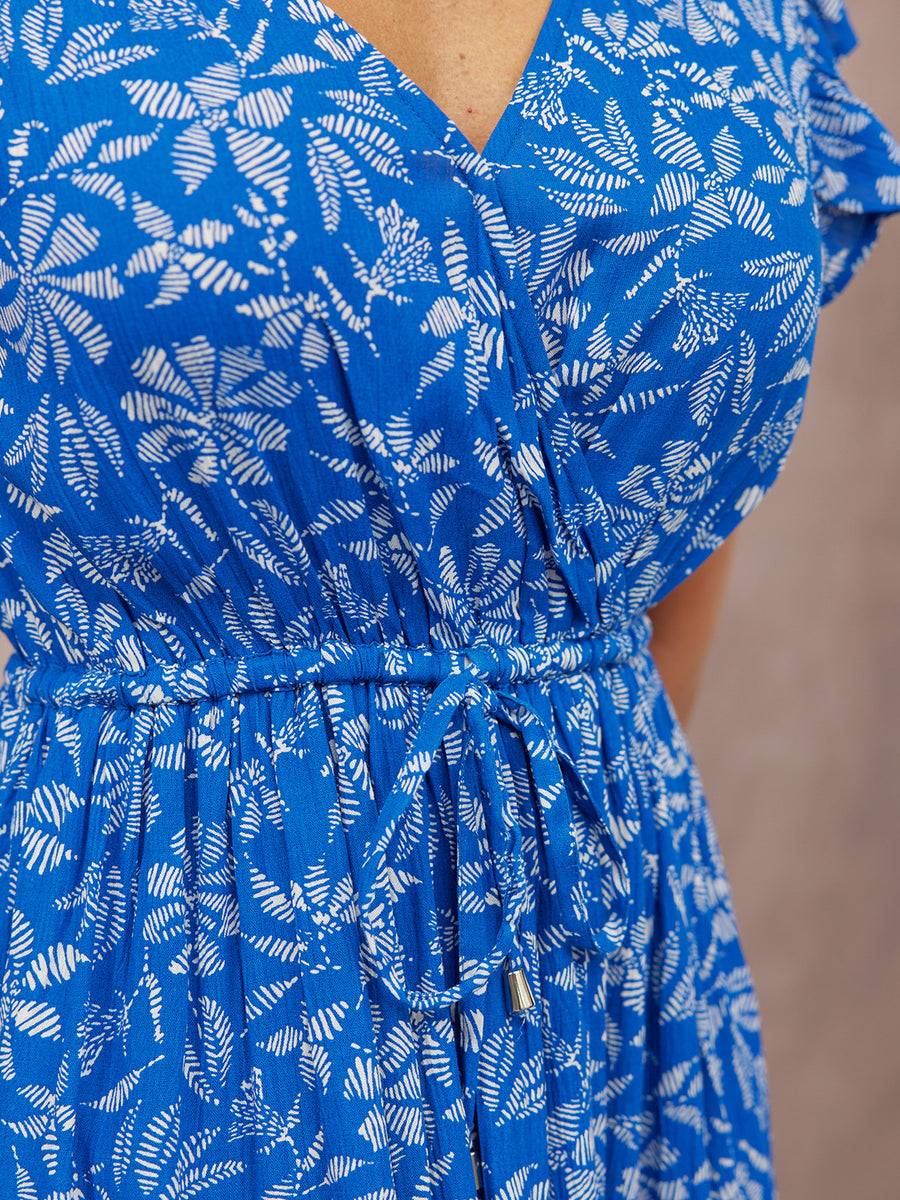 Close-up of a model wearing a blue and white leaf-print wrap dress with flutter sleeves and a drawstring elasticated waist.