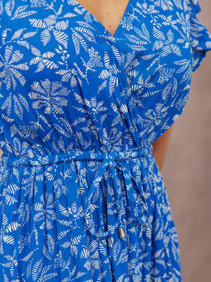 Close-up of a model wearing a blue and white leaf-print wrap dress with flutter sleeves and a drawstring elasticated waist.