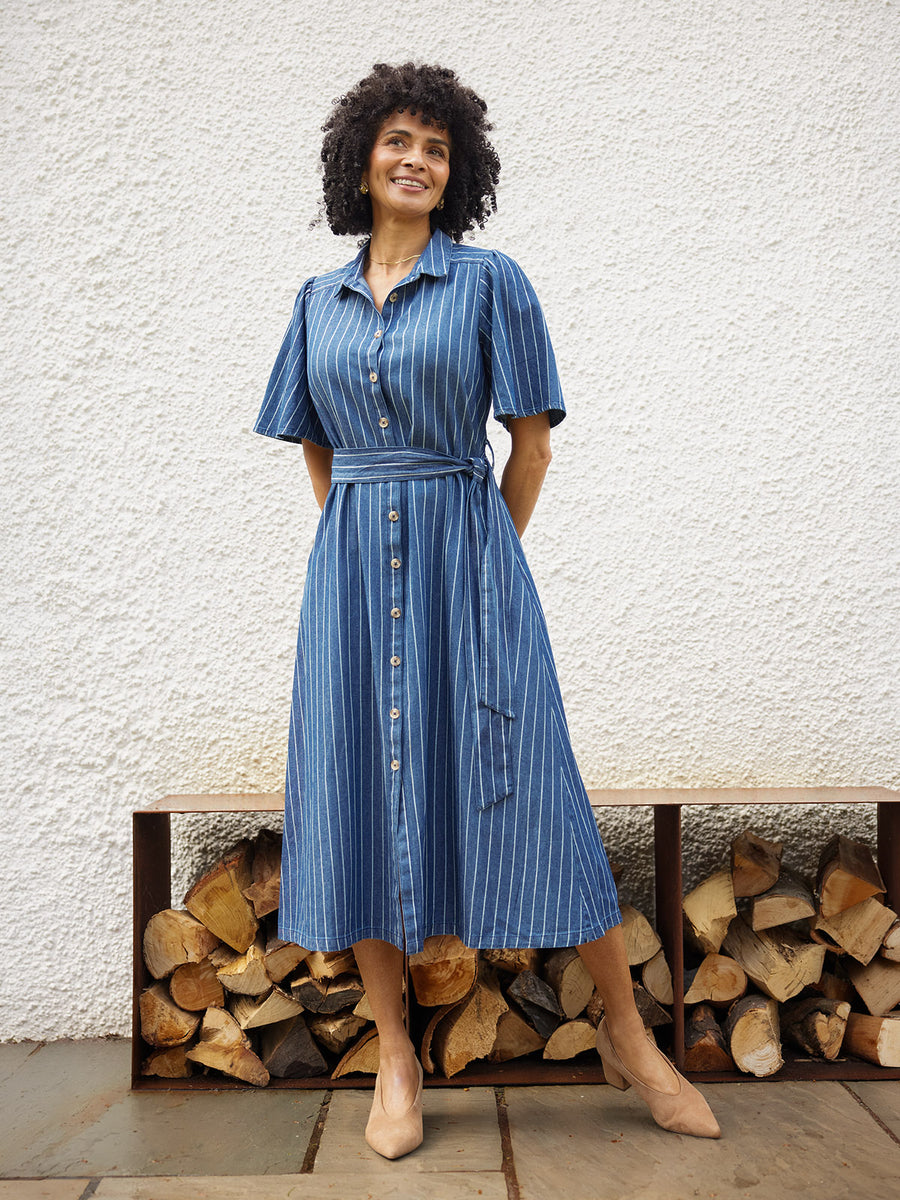 Model wearing a blue striped midi shirt dress with flutter sleeves, button front, and tie waist, styled with nude heels…