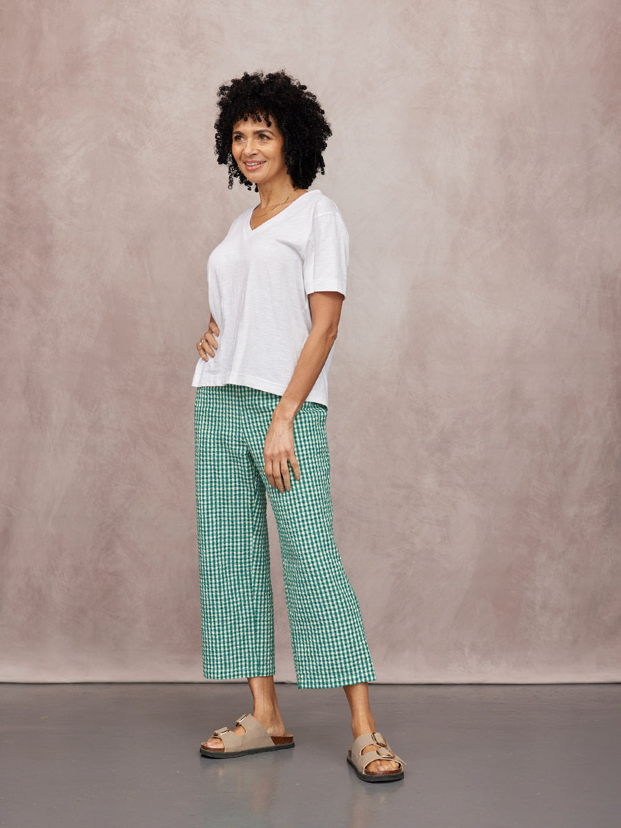 Rhianna Culotte in green gingham worn with a white v-neck tee and beige sandals against a neutral studio backdrop.