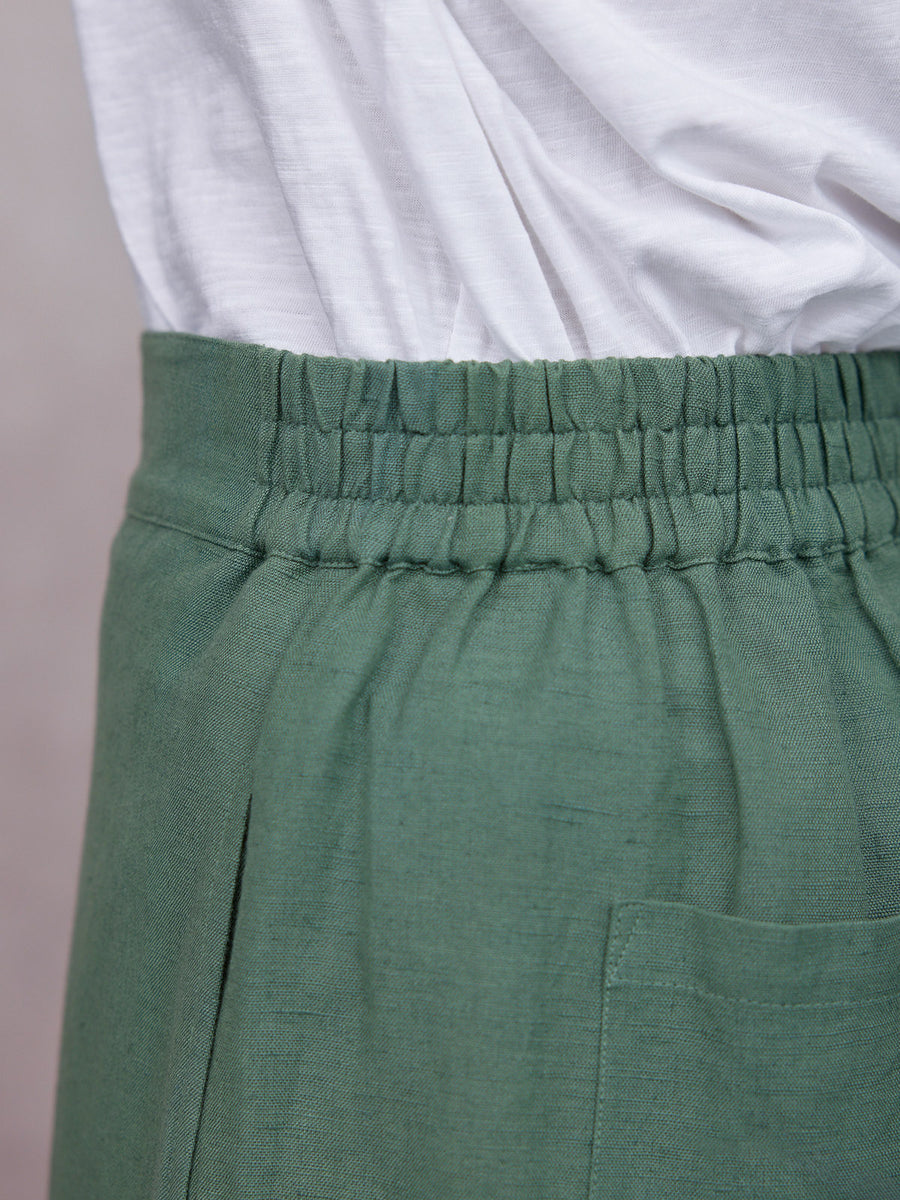 Myrtle Barrel Leg Trouser in sage green linen with elasticated waistband and patch pocket, paired with white tee
