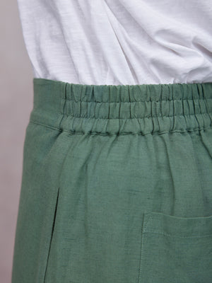 Myrtle Barrel Leg Trouser in sage green linen with elasticated waistband and patch pocket, paired with white tee