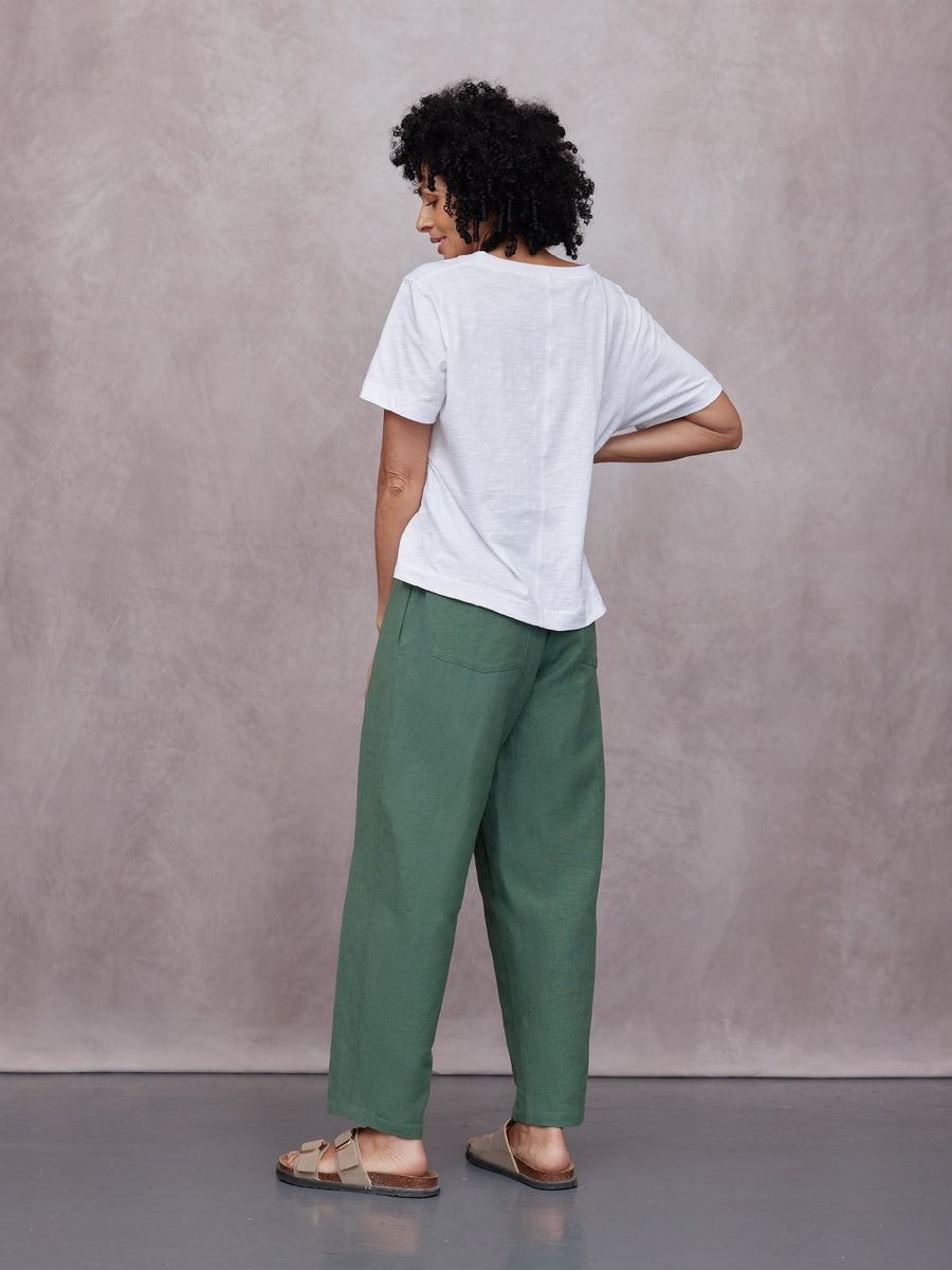 Myrtle Barrel Leg Trouser in green, worn with a white tee and sandals, showing relaxed wide-leg fit and back patch pocket