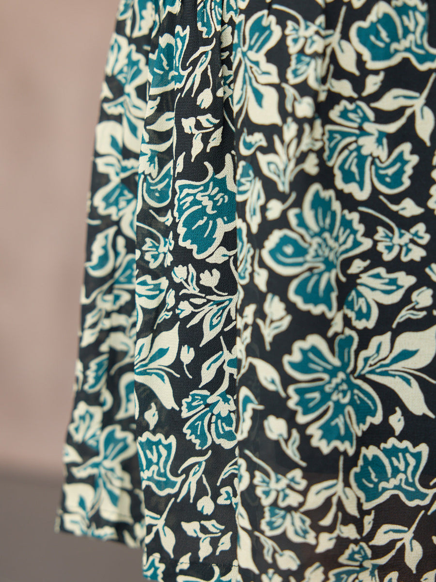 Close-up of a flowy skirt in a dark navy floral print with teal and cream botanical motifs.