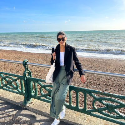 Smiling woman on the beach wearing green sustainable high waist trousers