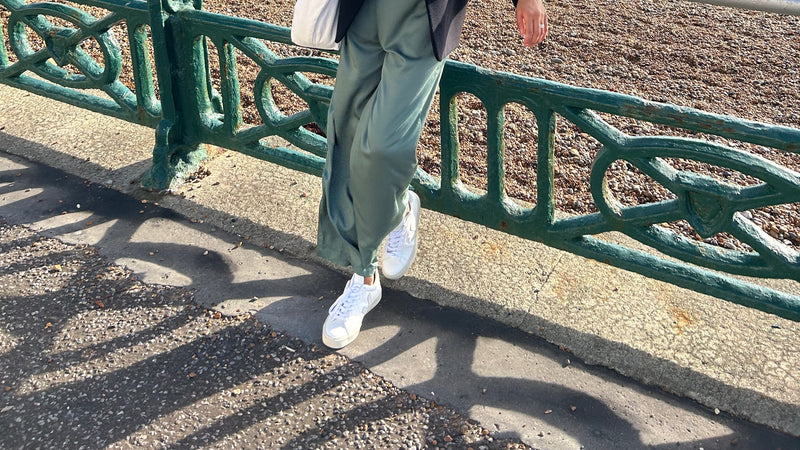 Smiling woman on the beach wearing green sustainable high waist trousers