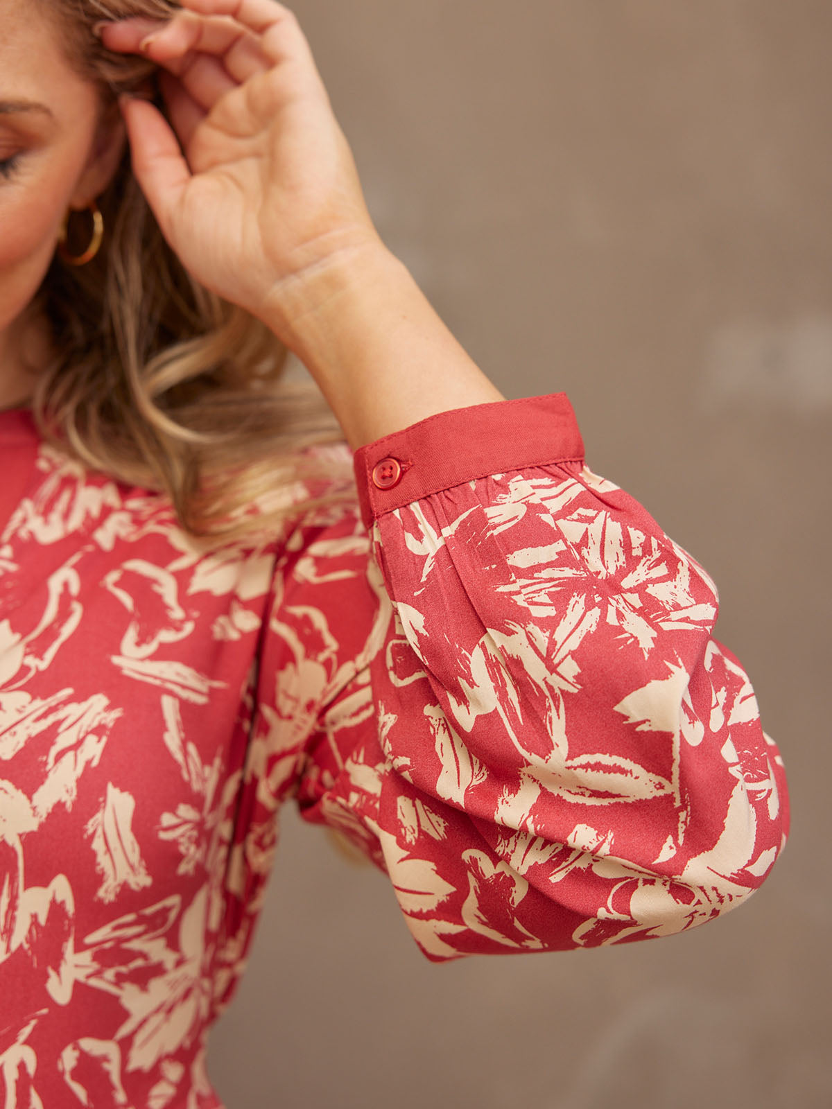 Close-up of a floral patterned red and cream blouse with puffed sleeves.
