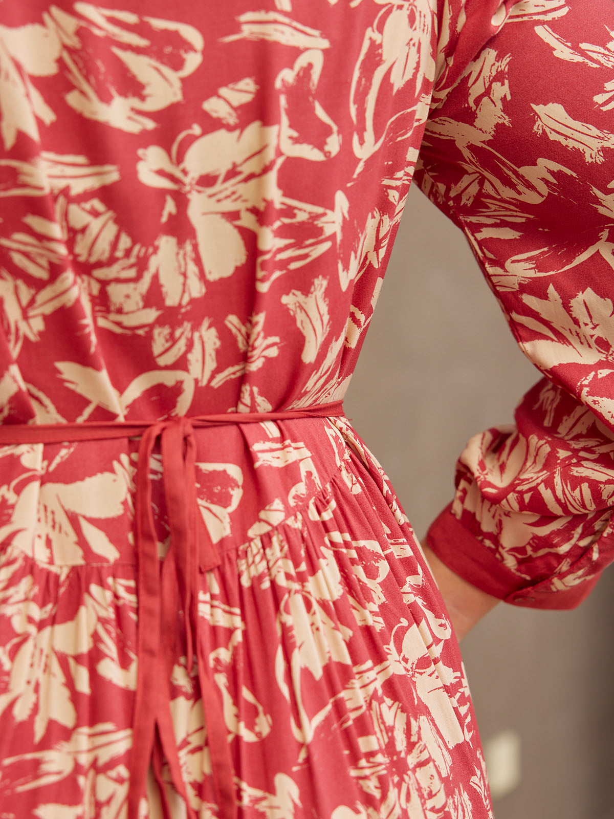 Back view of a red floral-patterned dress with a tied waist.