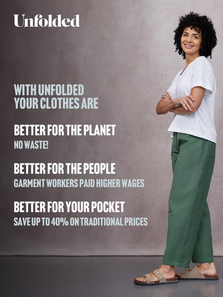 Unfolded Myrtle Barrel Leg Trouser in green, styled with a white tee and beige sandals on a smiling woman, studio background.