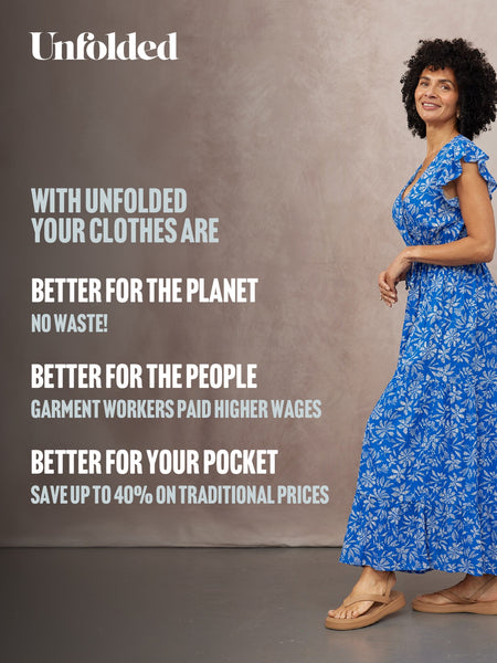 Model wearing a blue floral maxi dress with ruffle cap sleeves and tan flatform sandals against a grey background.