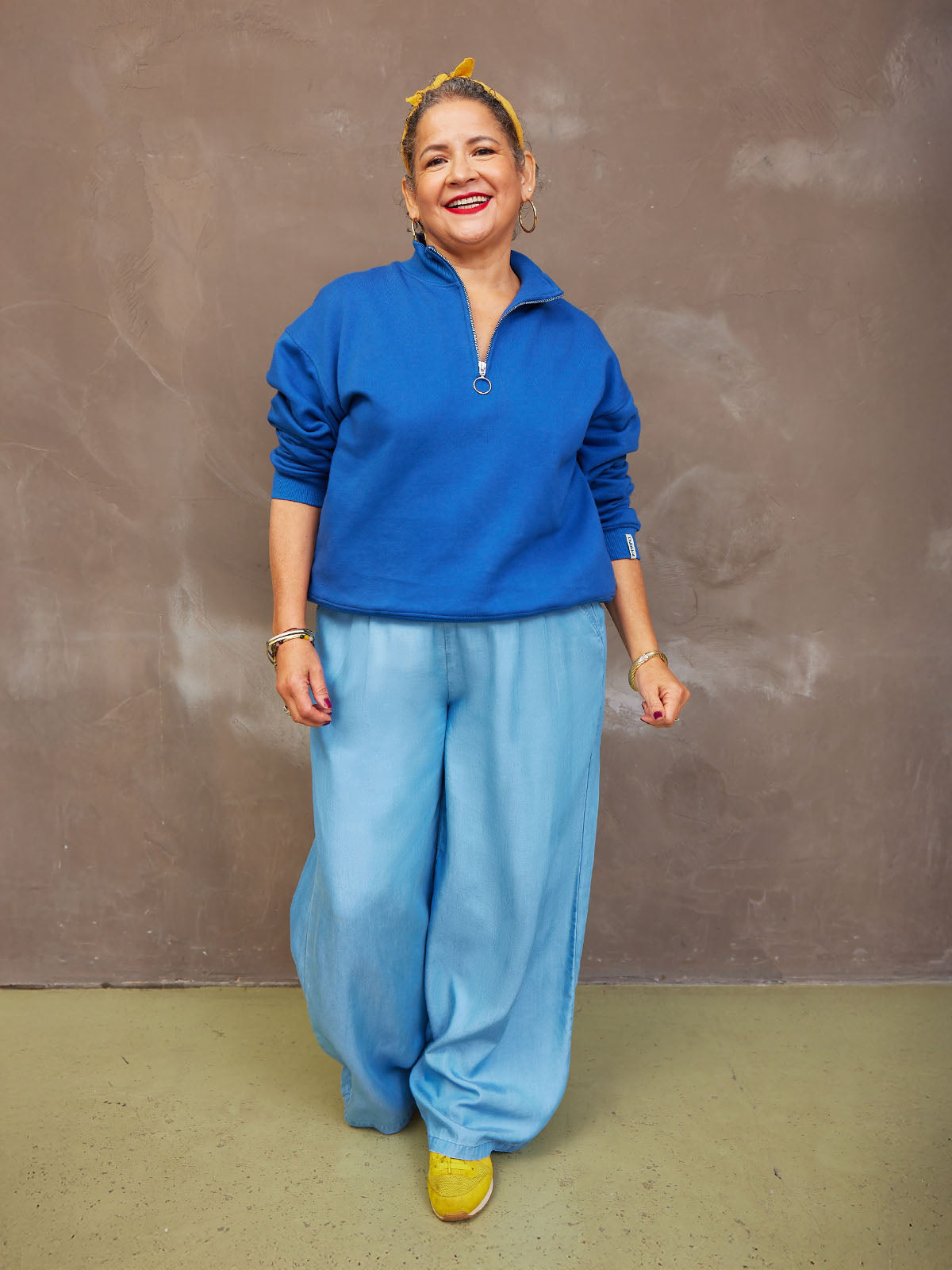 Person in a pink top smiling against a textured brown background.