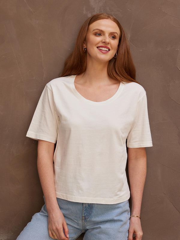 A model looking to the side, wearing the sustainable Lucy white t-shirt paired with jeans.