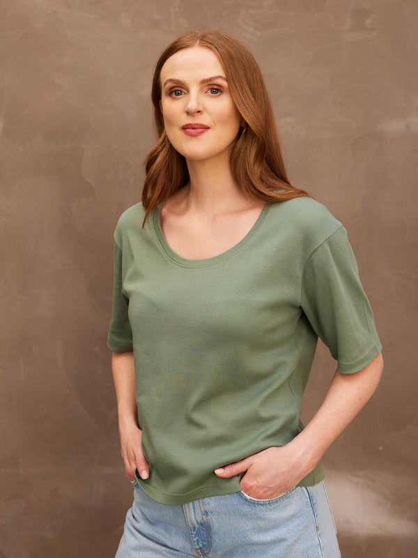 A model looking at the camera with her hands in her pockets, wearing the sustainable Lucy khaki t-shirt paired with jeans.