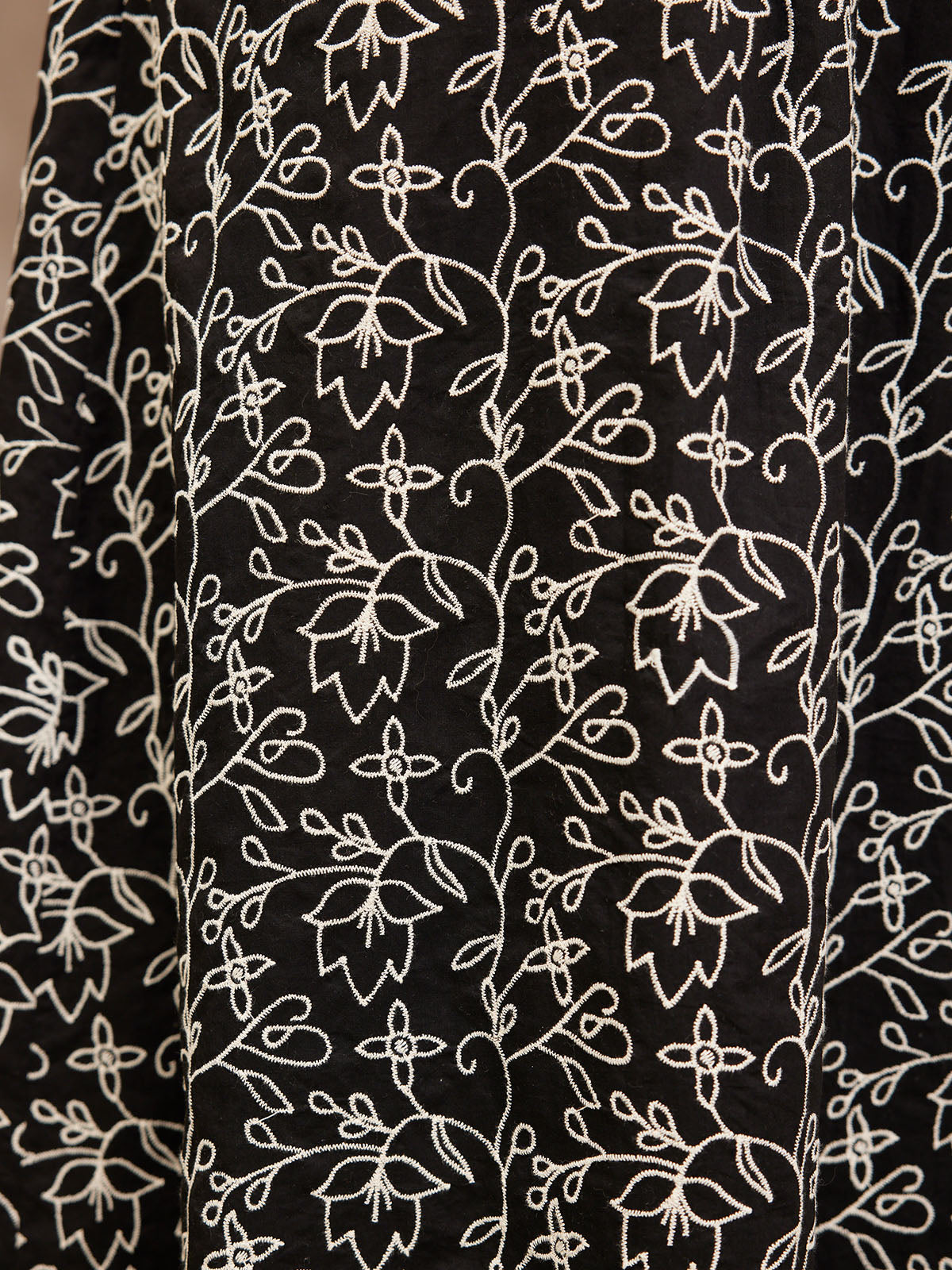 Black fabric with intricate white floral embroidery pattern.