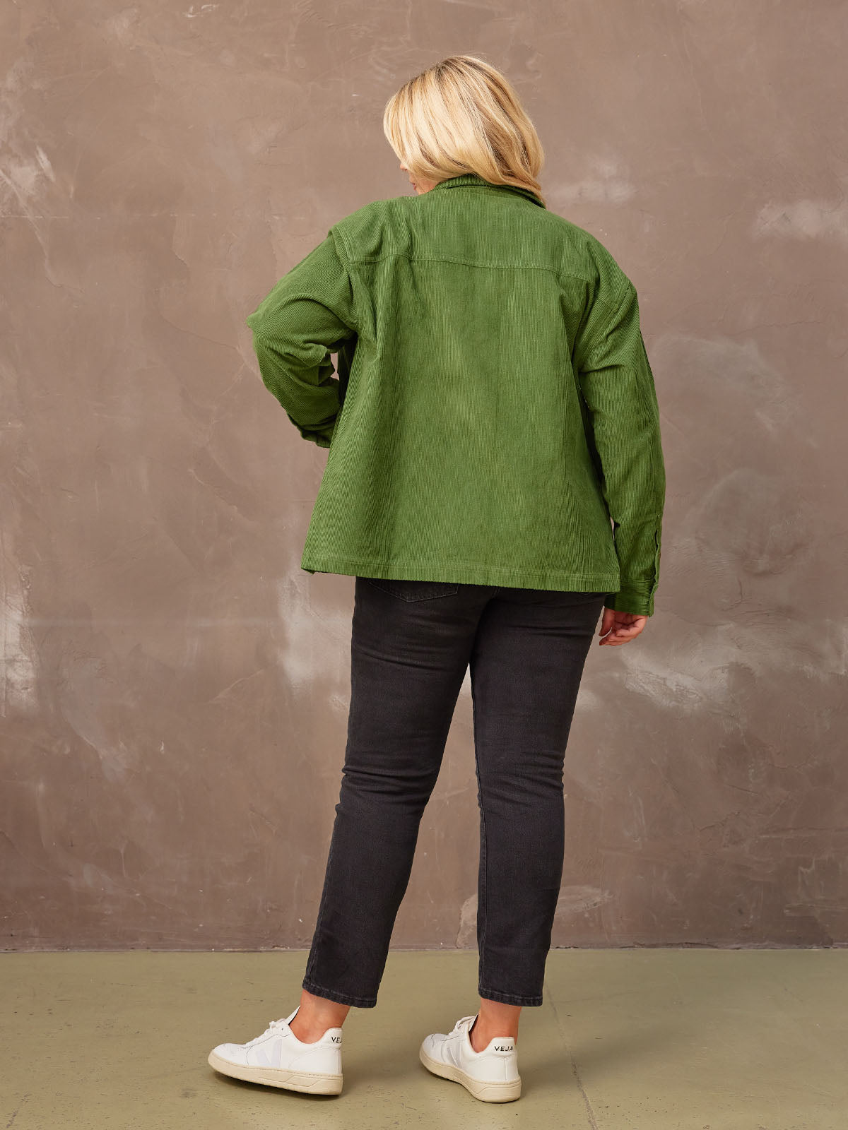 Backview of a model wearing a olive coloured corduroy Yasmynn shacket, looking at the ground. 