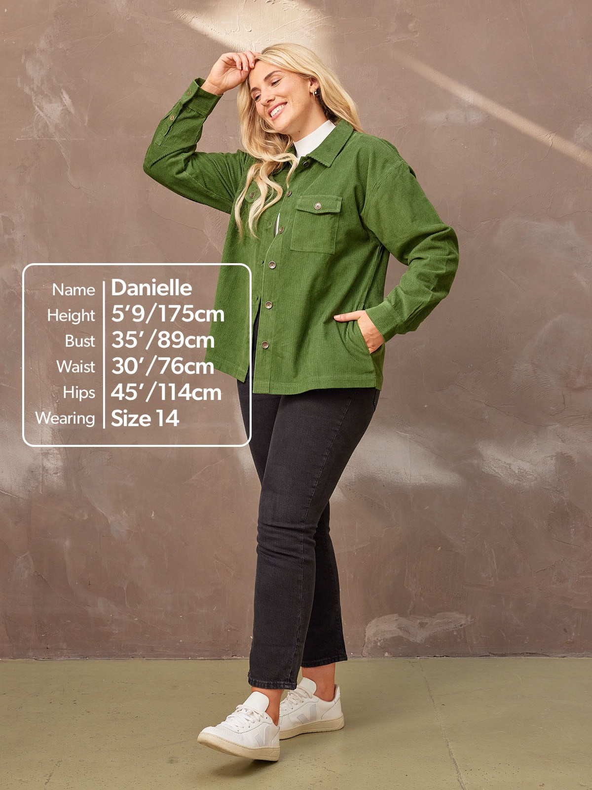 Smiling model looking to the side wearing the sustainable Yasmynn shacket in  olive, paired with a white top and black trousers. Picture features a text bubble with measurements.