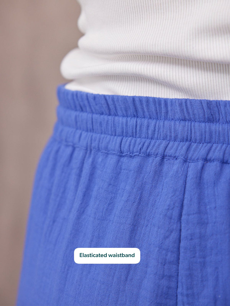 Close-up of Joy Cotton Crinkle Trouser in cobalt blue showing elasticated waistband, worn with a white top
