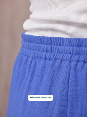 Close-up of Joy Cotton Crinkle Trouser in cobalt blue showing elasticated waistband, worn with a white top