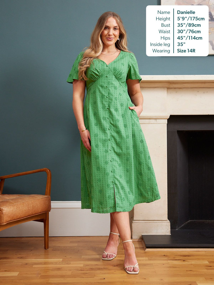 Allegra Broderie Dress in green – V-neck, flutter sleeves, button front & floral eyelet fabric, midi length, worn with white heels