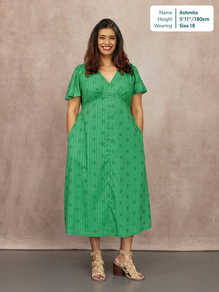 Allegra Broderie Dress in green, V-neck, flutter sleeves, button-front midi length with floral eyelet detail, worn with block-heel sandals