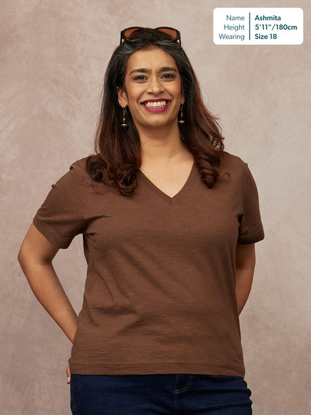 Cathy V-neck Tee in brown, worn by Ashmita, size 18, 5'11", paired with dark blue jeans against a neutral studio background.