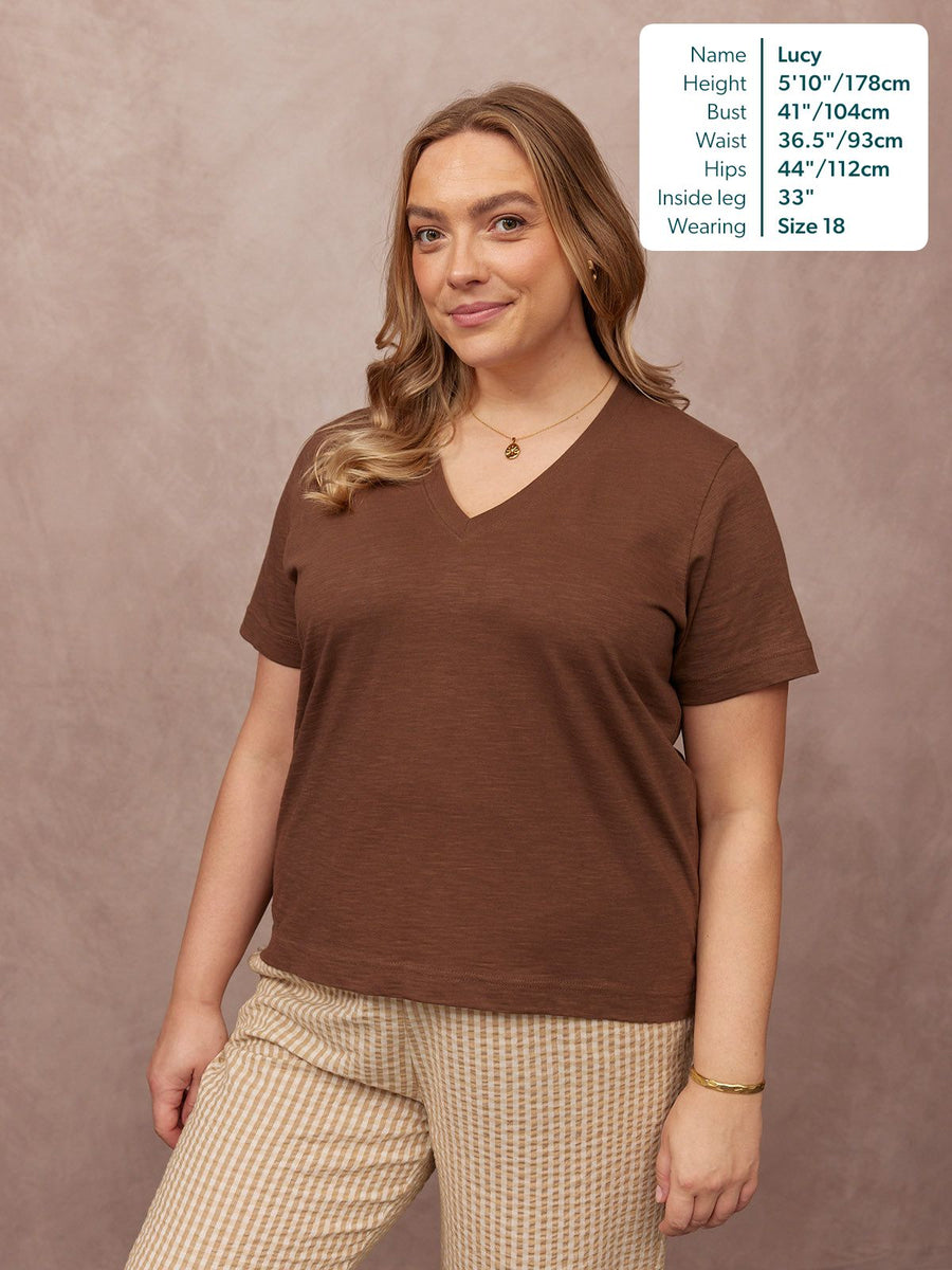 Cathy V-neck Tee in brown, worn by a size 18 model with striped trousers against a neutral studio background
