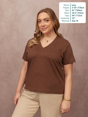 Cathy V-neck Tee in brown, worn by a size 18 model with striped trousers against a neutral studio background