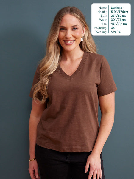 Cathy V-neck Tee in brown, worn by a size 14 model with black trousers against a dark blue background