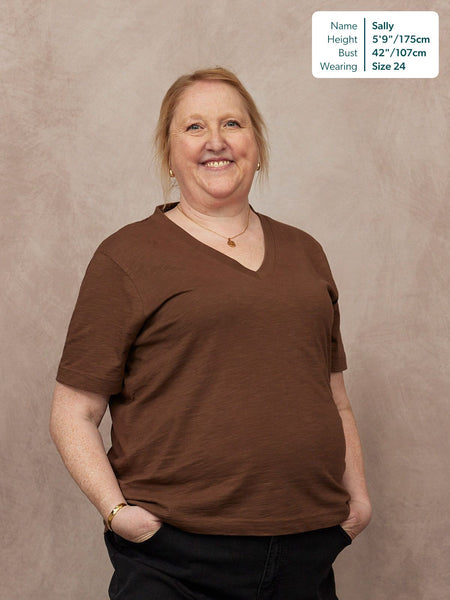 Cathy V-neck Tee in brown, worn by Sally, size 24, 5'9". Relaxed fit short-sleeve t-shirt with V-neckline, paired with black jeans.