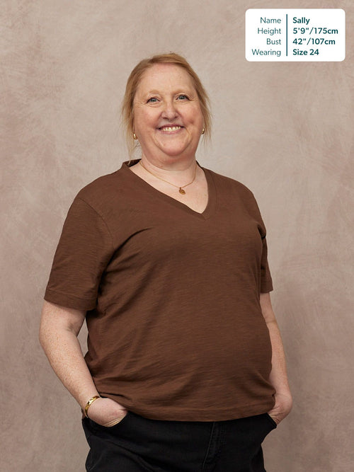 Cathy V-neck Tee in brown, worn by Sally, size 24, 5'9". Relaxed fit short-sleeve t-shirt with V-neckline, paired with black jeans.