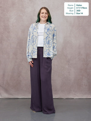 Model wearing wide-leg dark purple trousers with a drawstring waist, styled with an open blue floral shirt and white tee.