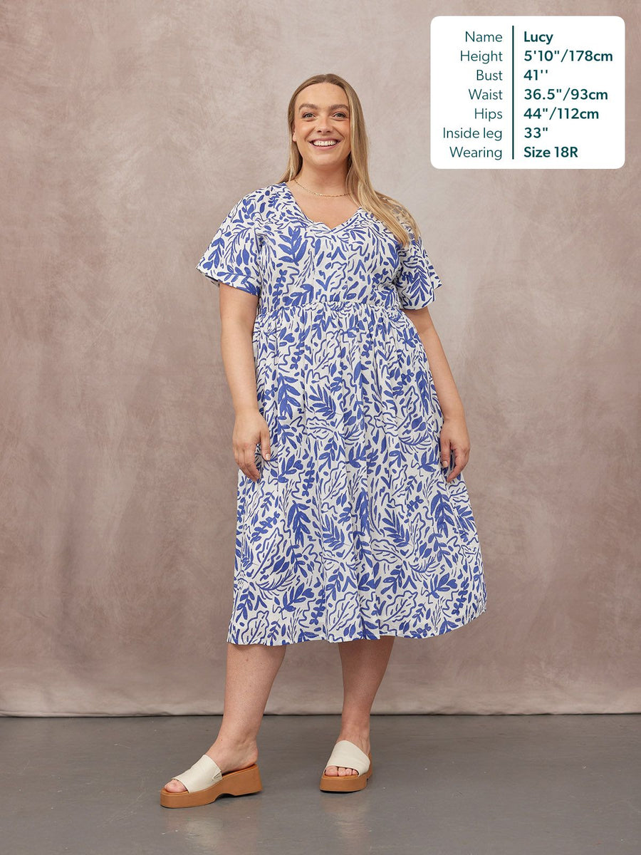 Model wearing a white midi dress with a blue abstract leaf print, flutter sleeves, V-neck, and elasticated waist, styled…