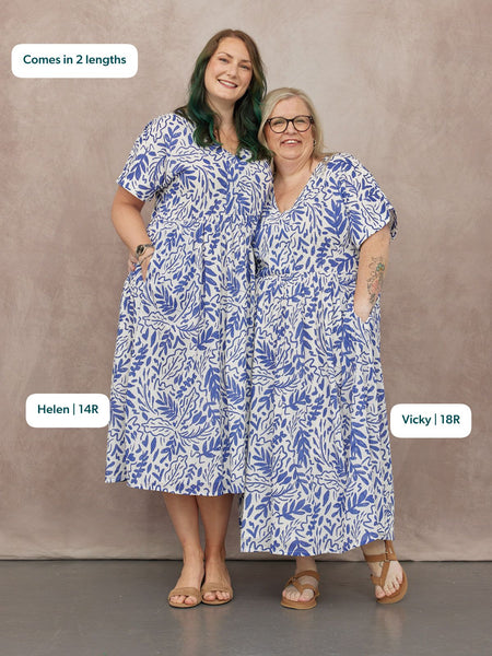 Two models wearing white and blue botanical print midi dresses with short sleeves, v-neckline, and side pockets, styled…
