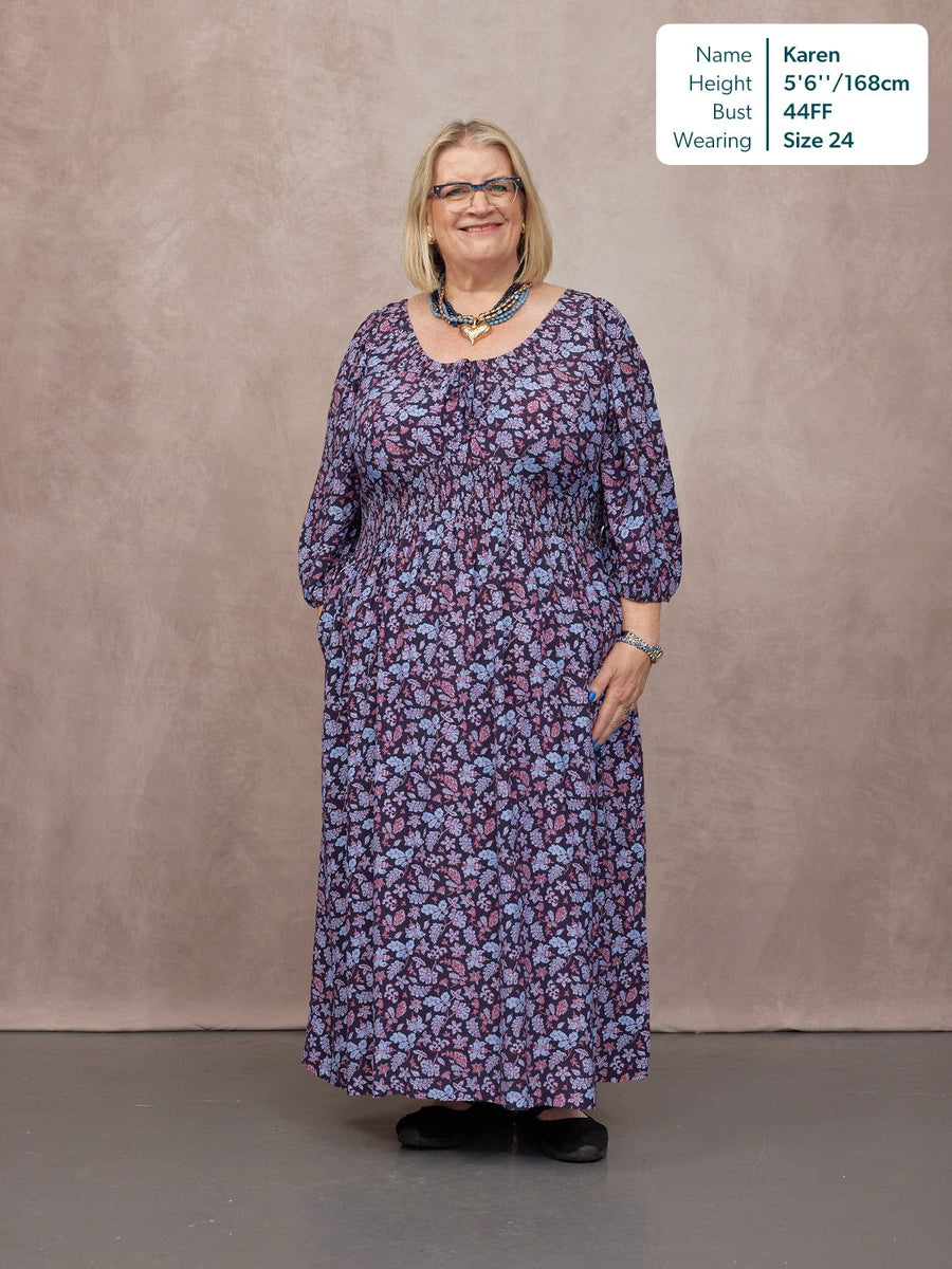 Model wears a navy floral maxi dress with shirred waist, three-quarter sleeves, and scoop neckline