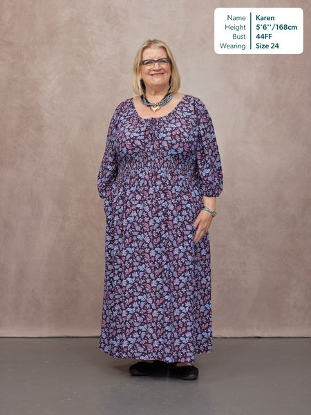 Model wears a navy floral maxi dress with shirred waist, three-quarter sleeves, and scoop neckline