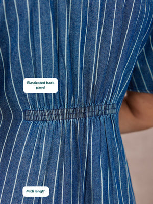 Close-up of a blue pinstripe denim midi dress showing an elasticated back waist panel with gathered fabric detail.