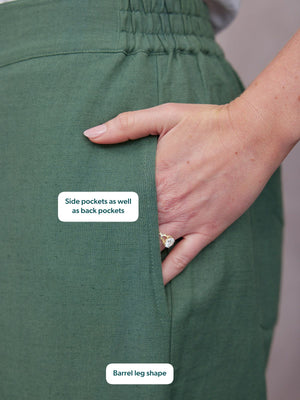 Myrtle Barrel Leg Trouser in green linen, close-up of side pocket with elasticated waist, hand resting in pocket