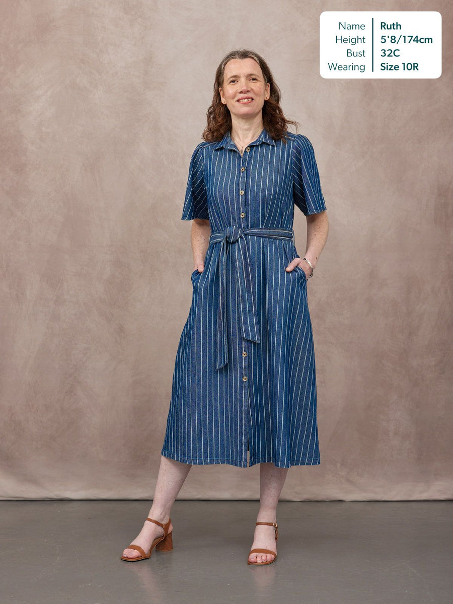 Model wears a navy striped short-sleeve shirt dress with a tie waist and button-through front, styled with tan heeled…