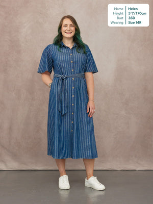 Model wearing a blue pinstripe midi shirt dress with short sleeves, button front, and tie waist, styled with white trainers.