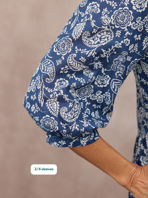 Close-up of a model's arm in a navy blue top with white paisley and floral print, featuring elasticated 3/4 puff sleeves.
