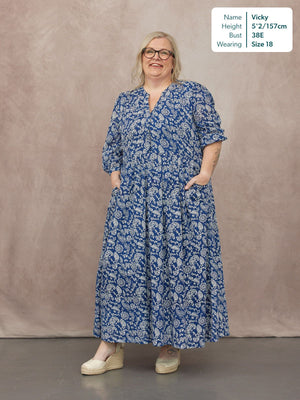 Model wearing a blue and white paisley maxi dress with a V-neckline, tiered skirt, and 3/4 sleeves, styled with espadrille…