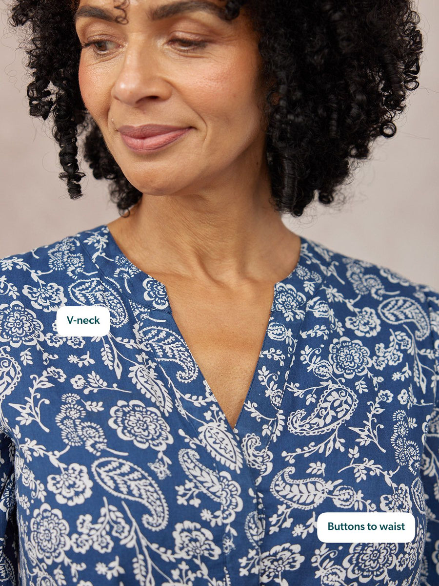 Close-up of a model wearing a blue and white paisley print blouse with a V-neck and button front detail.
