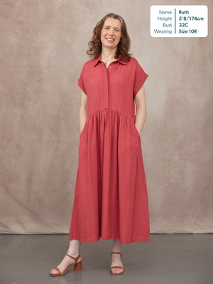 Model wearing a coral red midi shirt dress with a gathered skirt, short sleeves, collar, and side pockets, styled with tan…