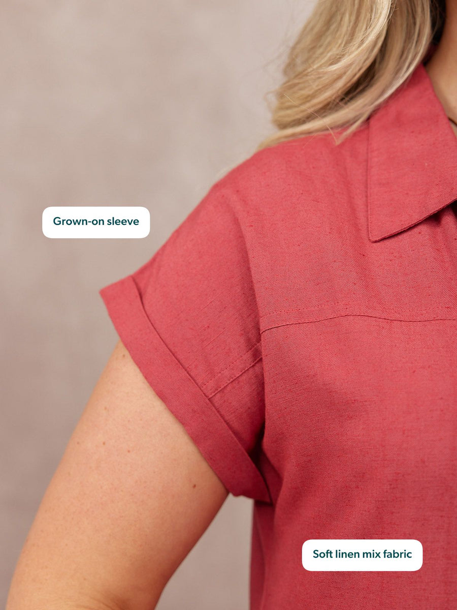 Close-up of a model wearing a raspberry red linen-mix top with a grown-on short sleeve and open collar.