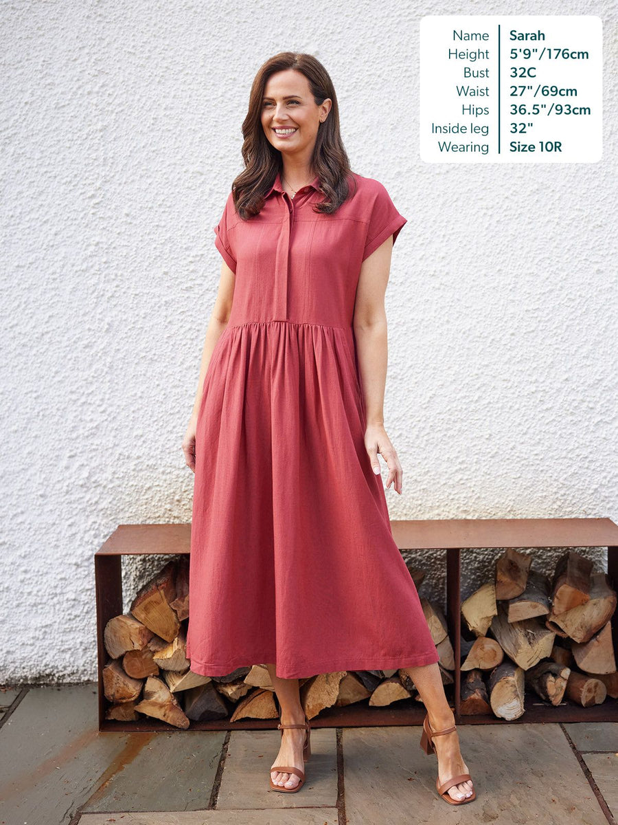 Model wearing a terracotta maxi shirt dress with a gathered skirt and cap sleeves, paired with tan block-heel sandals.