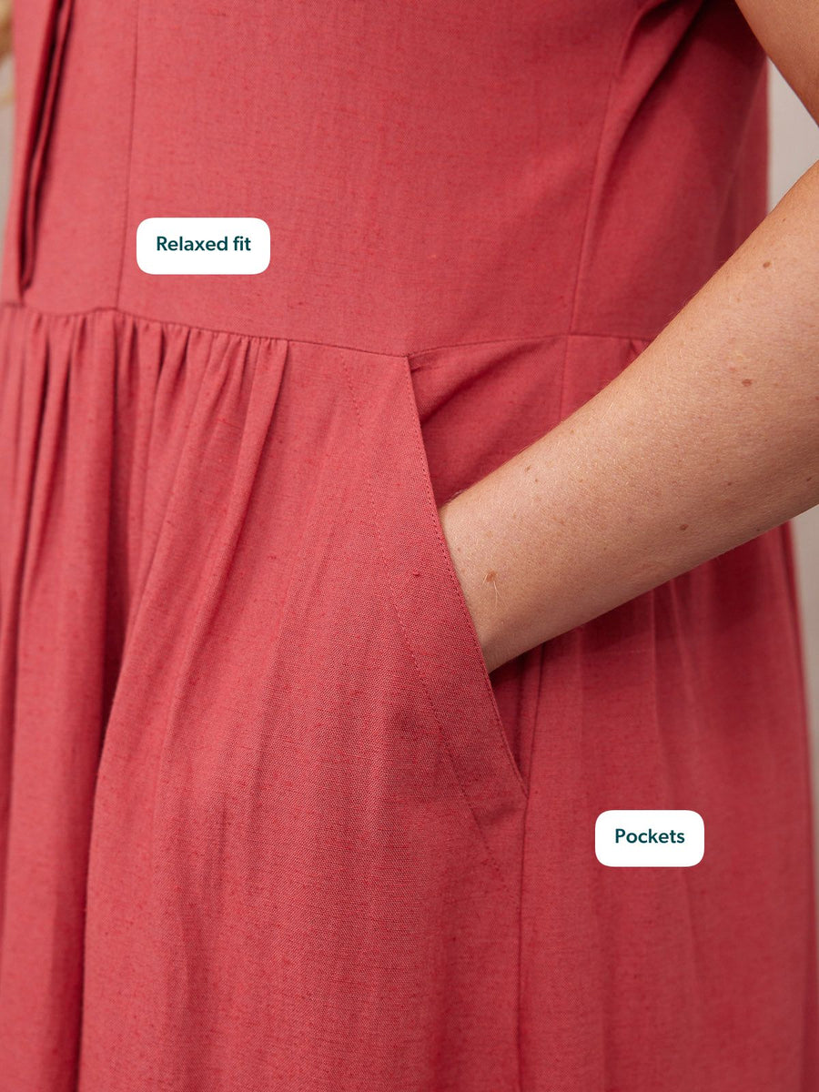 Close-up of a model's hand tucked into the side pocket of a relaxed-fit red linen dress with gathered skirt.