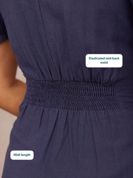 Close-up of the back of a navy midi dress on a model, highlighting wide shirred elastic waistband detail.