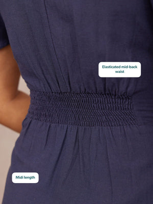 Close-up of the back of a navy midi dress on a model, highlighting wide shirred elastic waistband detail.