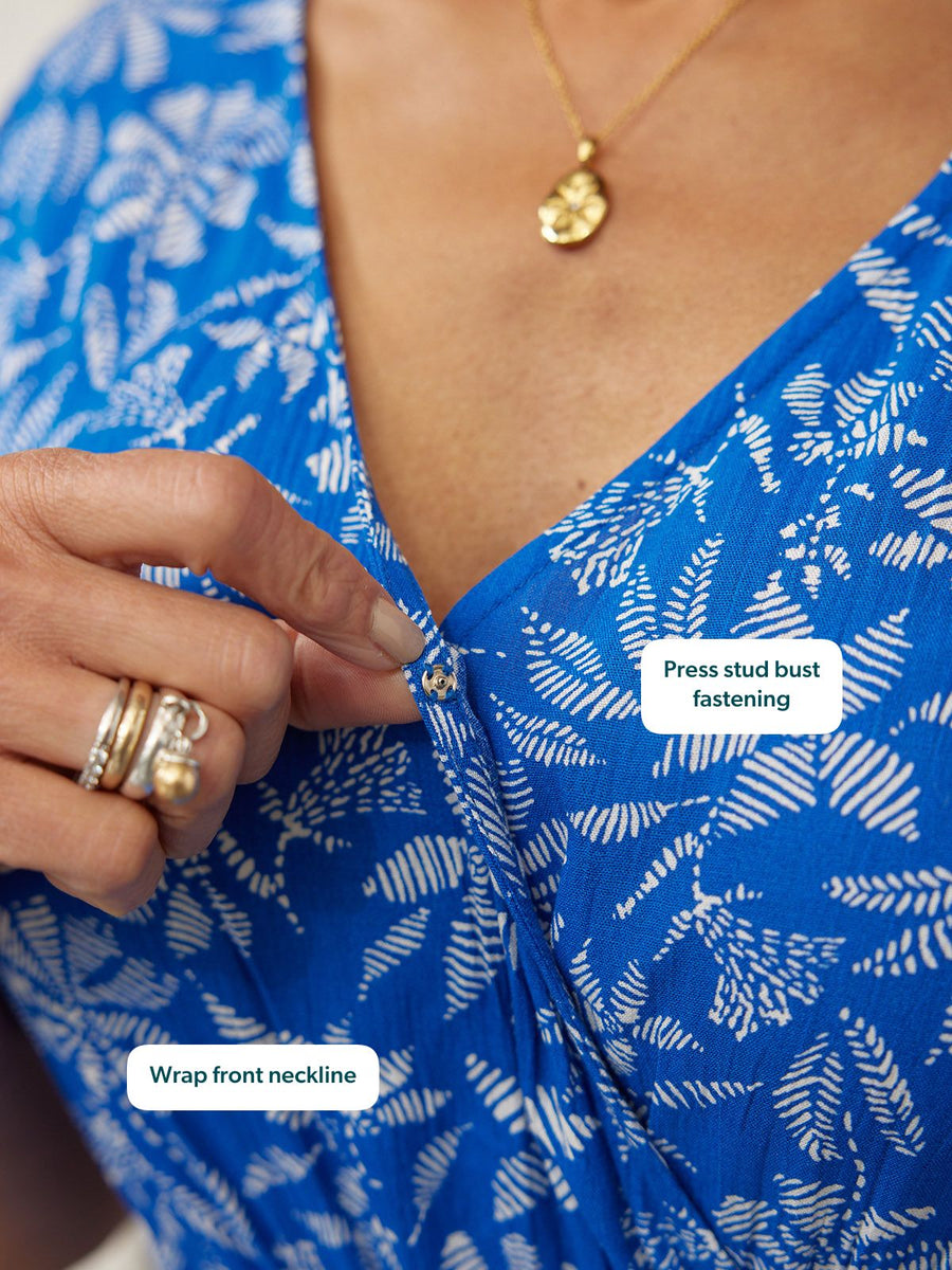 Close-up of a cobalt blue wrap-front dress with a white fern print, showing a press stud bust fastening.